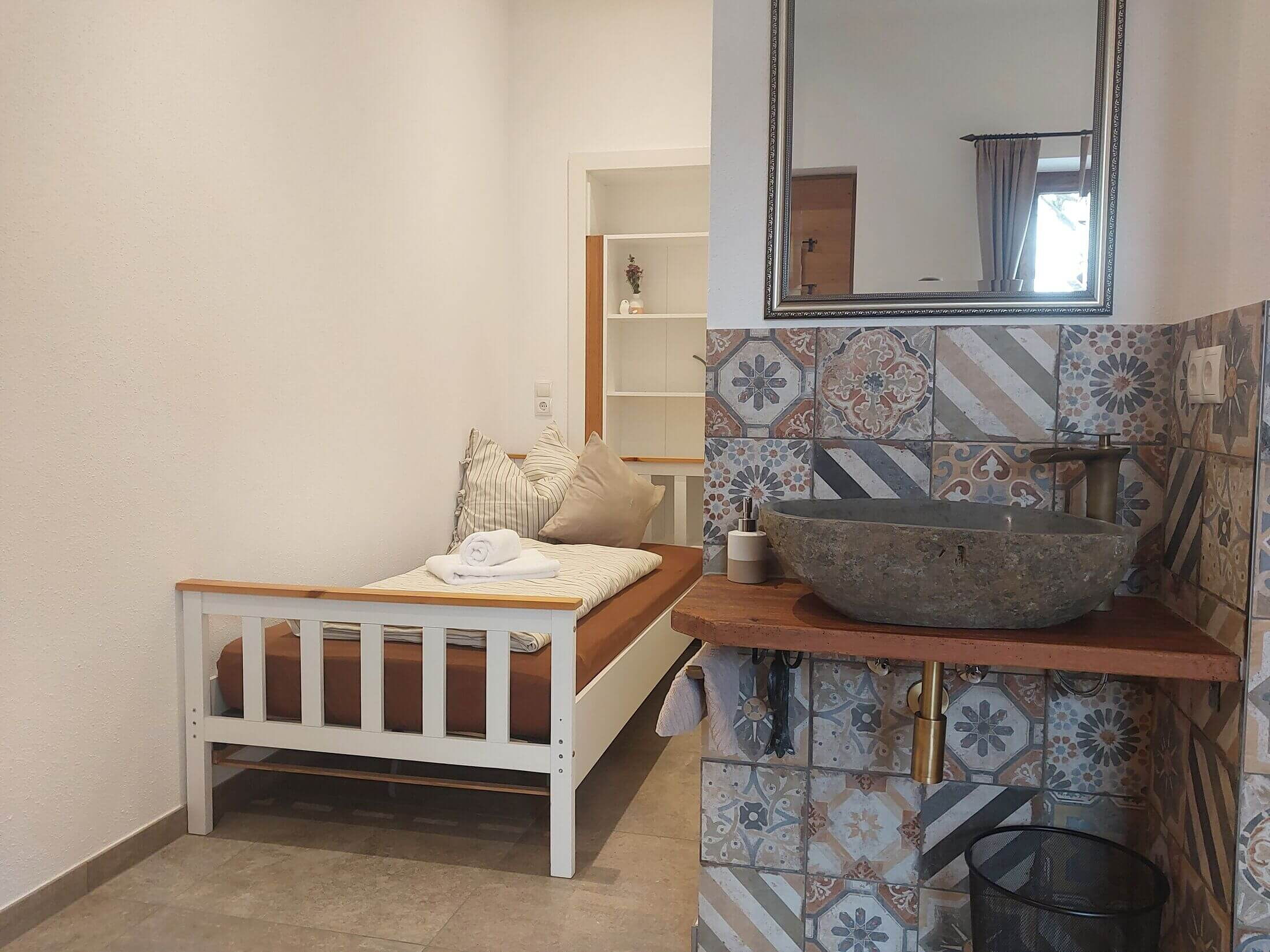 Die Ferienwohnung d'kloane Mühle mit dem zweiten Zimmer, zwei Einzelbetten und Steinwaschbecken.