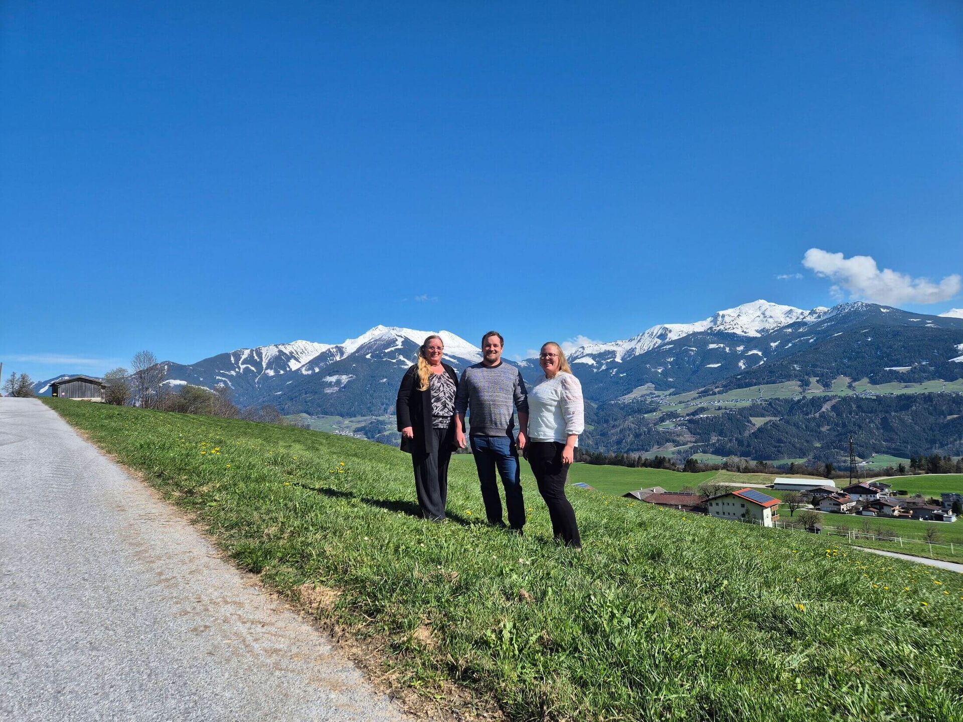 Das Team von Urlaubshütten mit Bergwelt im Hintergrund.