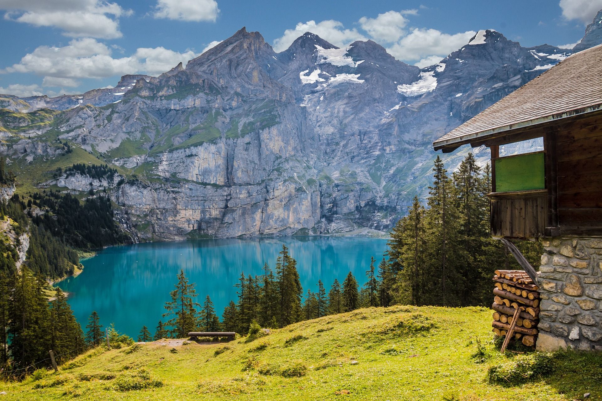 Panoramablick von einer Berghütte auf einen glitzernden Bergsee und die umliegenden Gipfel, ein perfekter Ort für Wanderer und Naturliebhaber.